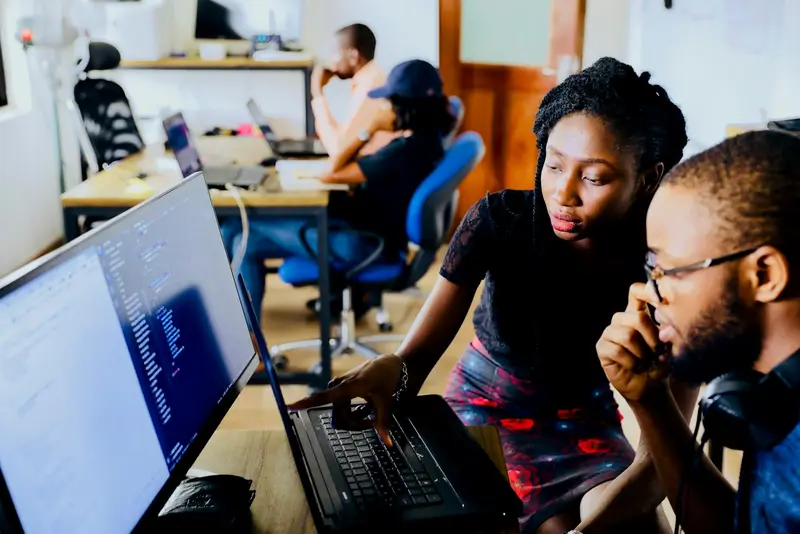 Two developers reviewing code together on a laptop